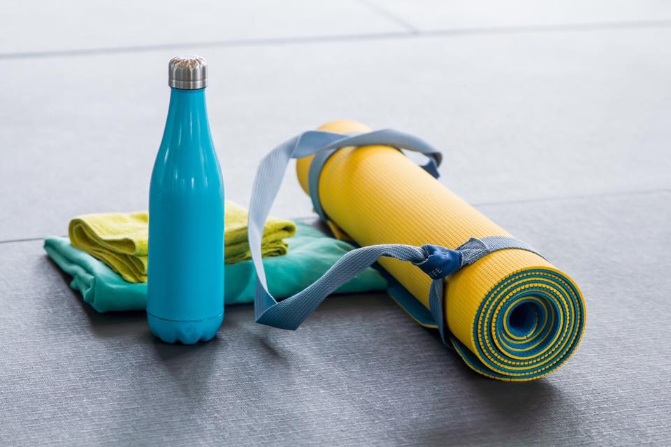  Hot yoga accessories laid out including mat, towels, water bottle